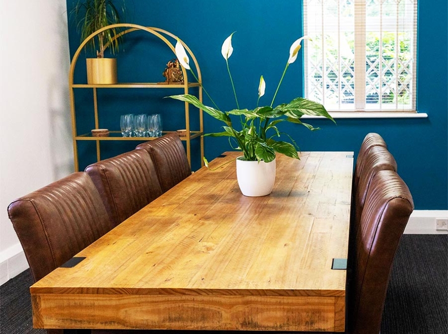 Meeting room wooden table with vegetarian leather chairs and teal wall.