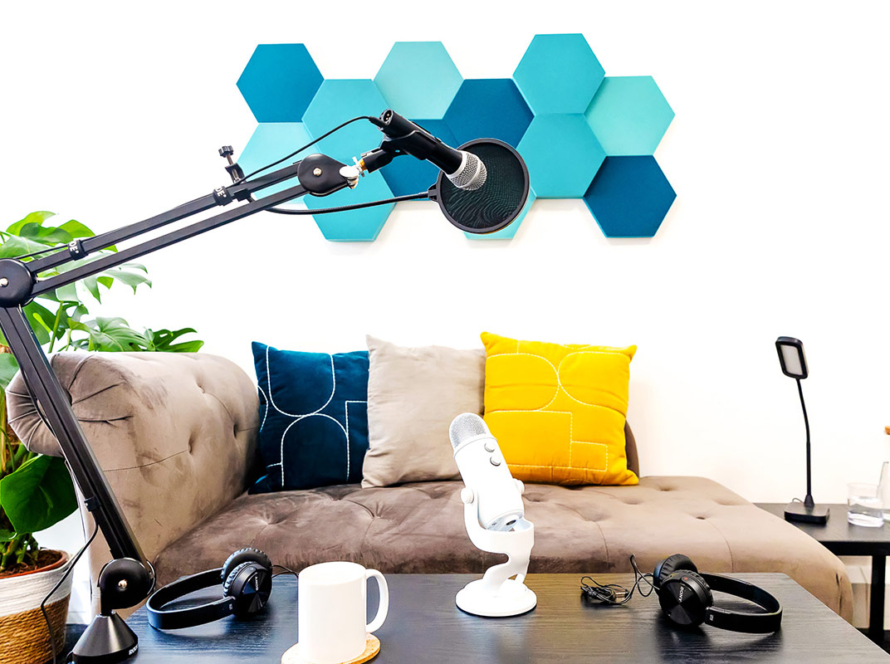 Sofa with brightly coloured chashions, mic arm, microphone and coffee table against a white wall.