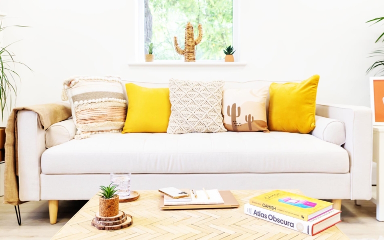 Yellow and neutral cushions on the neutral Createry coworking sofa with coffee table and books.