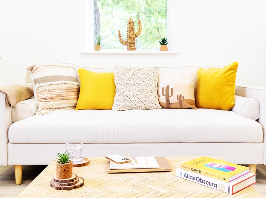 Yellow and neutral cushions on the neutral Createry coworking sofa with coffee table and books.