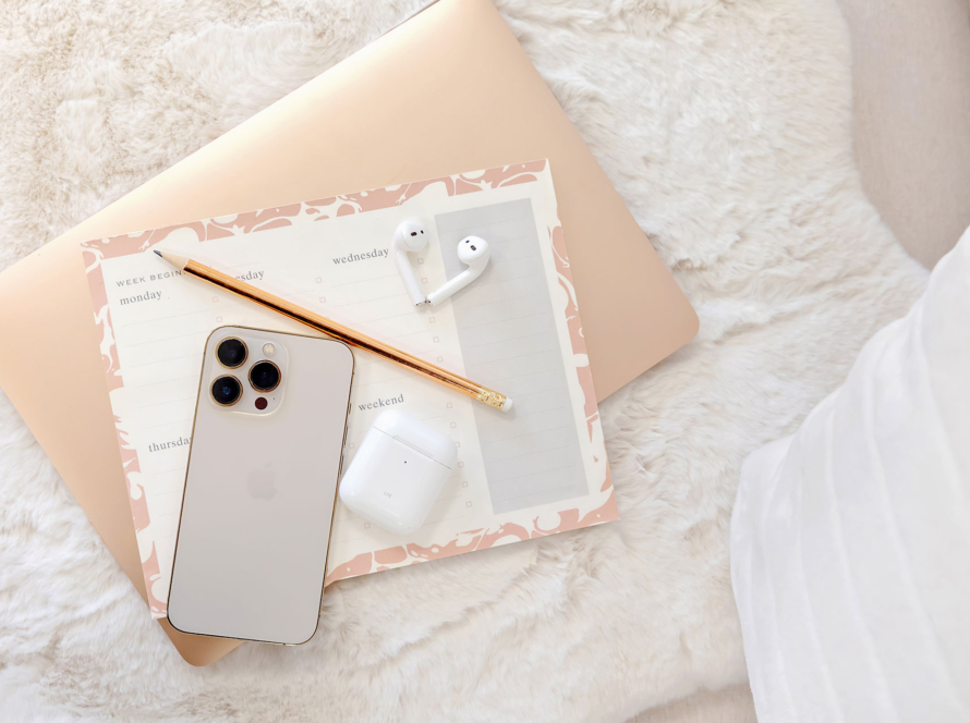 Laptop, planner, phone and pencil on white cushion