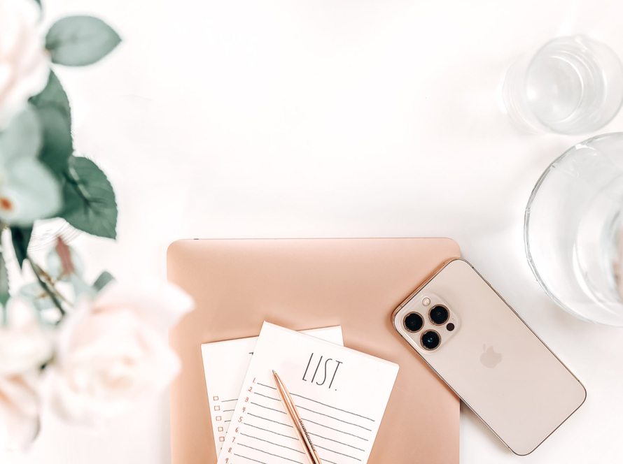 Laptop, phone, flowers, to do list pad on white desk