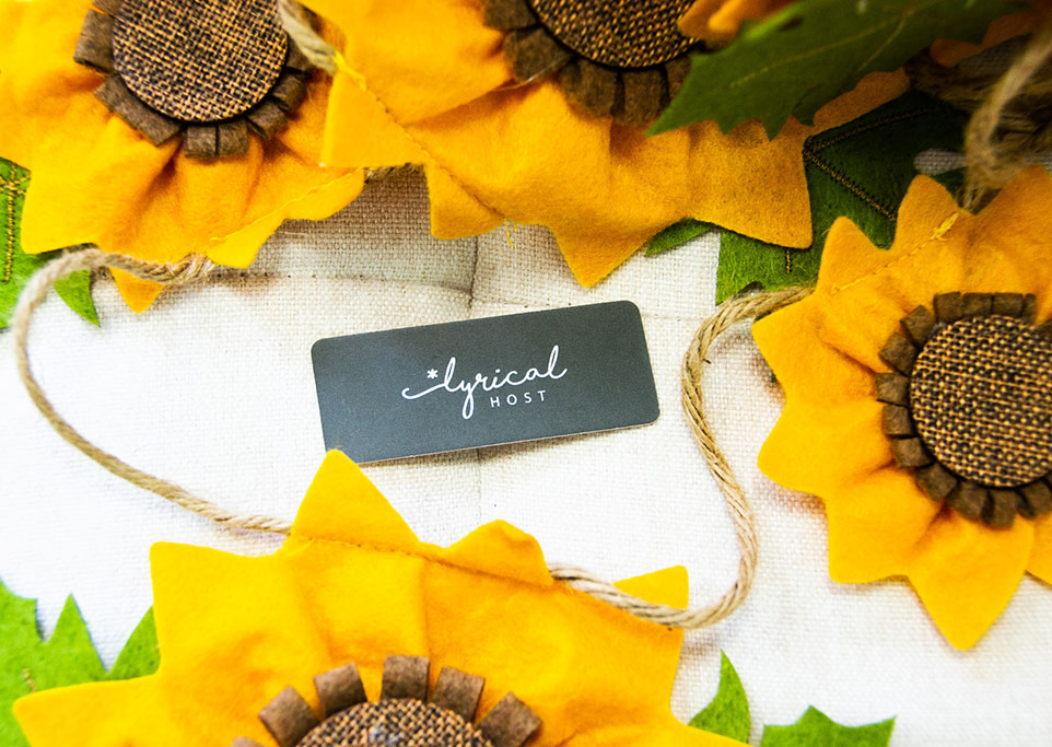 String of fabric sunflowers arranged around a Lyrical Host business crd