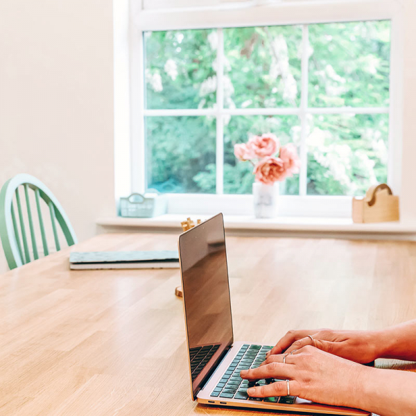 Hands on laptop keyboard on wooden desk.